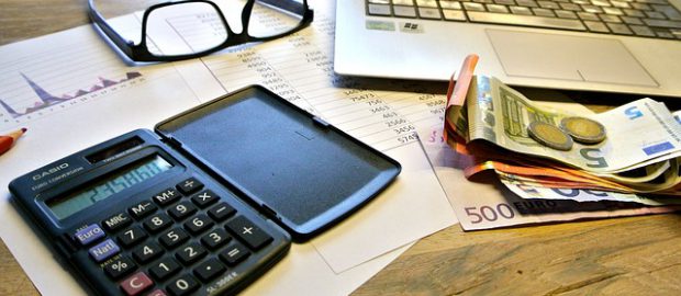 okulary, kalkulator, pieniądze i komputer na biurku