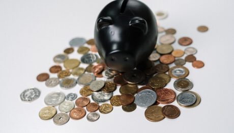 Czarna skarbonka w kształcie świnki, obok monety