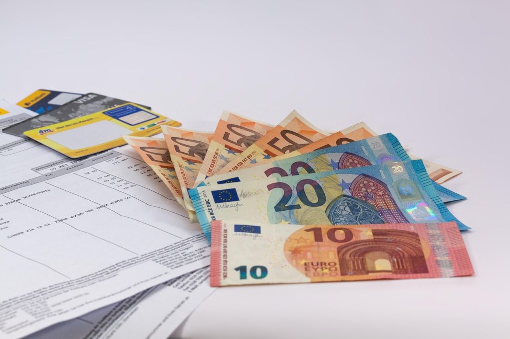 Banknoty euro ułożone na dokumentach finansowych i formularzu wniosku.