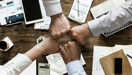 Zespół biznesowy przy biurku z dokumentami finansowymi i gadżetami elektronicznymi.