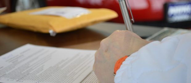 Podpisywanie dokumentu kredytowego długopisem przy biurku.
