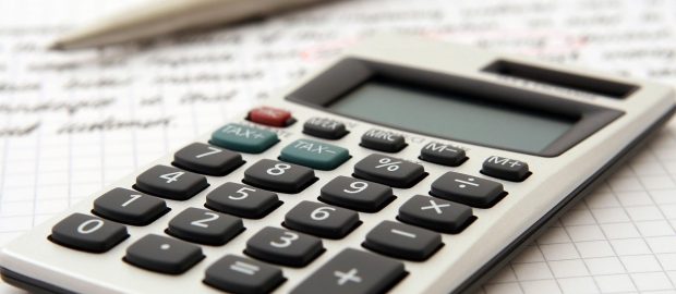 Kalkulator i długopis leżące na arkuszu z obliczeniami finansowymi.