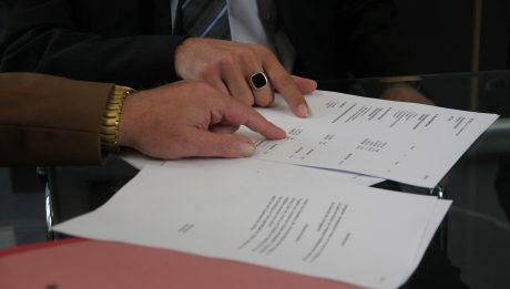 Dłonie wskazujące na dokumenty kredytowe podczas podpisywania umowy