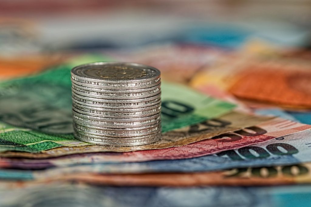 Stos monet ułożony na kolorowych banknotach.