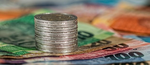 Stos monet ułożony na kolorowych banknotach.