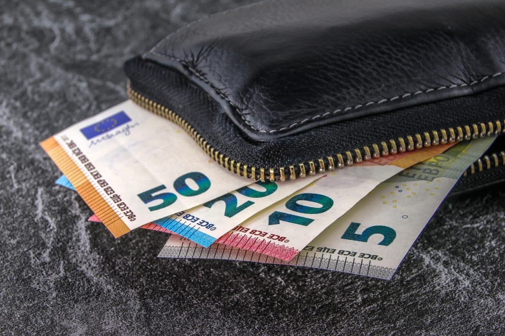 Skórzany portfel z banknotami euro wystającymi z zamka błyskawicznego.