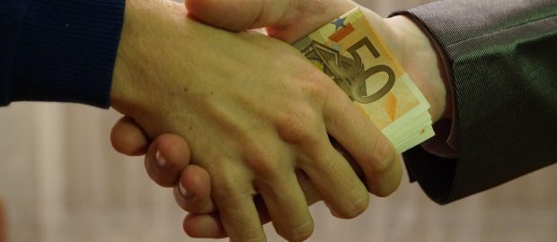 Uścisk dłoni z przekazywanym banknotem.