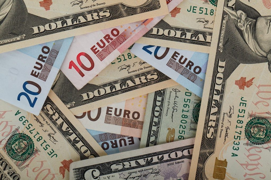 Banknoty dolarowe i euro ułożone obok siebie.