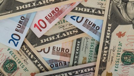 Banknoty dolarowe i euro ułożone obok siebie.