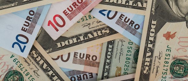 Banknoty dolarowe i euro ułożone obok siebie.